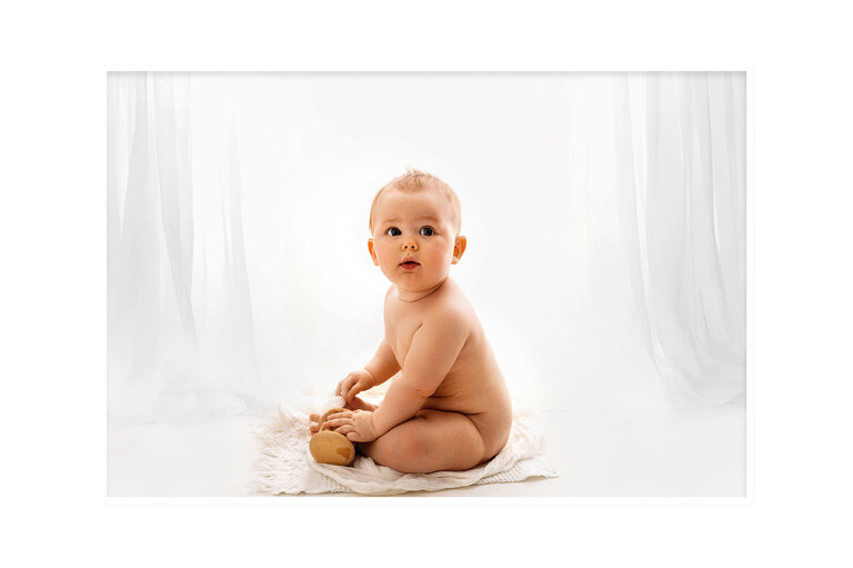baby boy sitting on the floor white backdrop with curtains